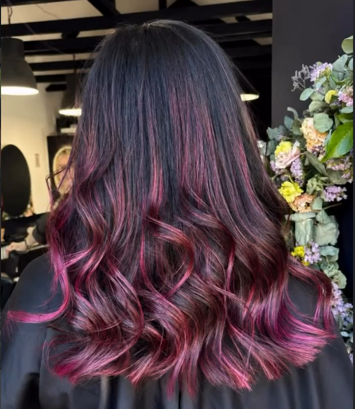 Dark brunette hair with burgundy and pink balayage waves in the salon